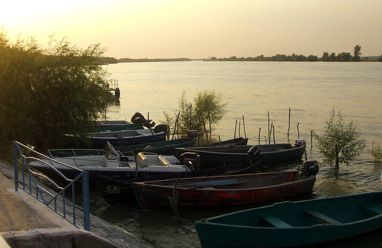 Des barques sont amarrées au quai sous un couché de soleil.