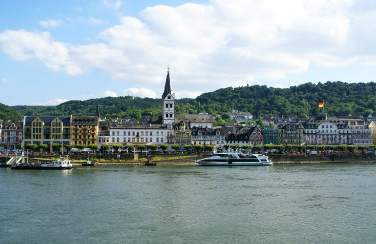 Vue de la ville. Il y a l'eau au premier plan, la vile et en fond une coline.