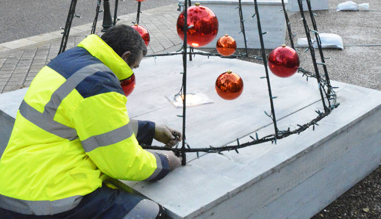 Un agent du service fêtes et manifestations est en train d'installer les décorations de Noël sur la place du château royal d'Amboise.