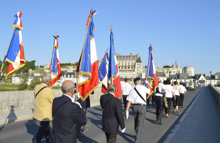 Déambulation patriotique sur le pont d'Amboise. Vue sur le Château royal et un ciel bleu. Au premier plan, les portes drapeaux.