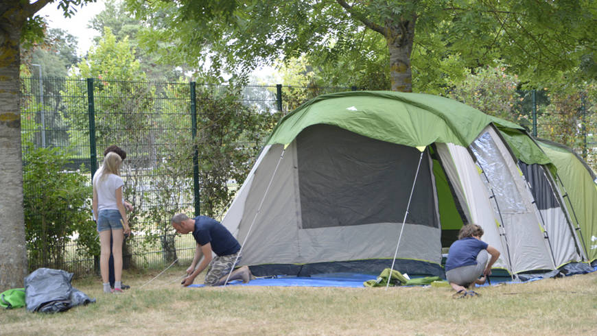 Des personnes monte une grande tente dans le camping de l'Île d'Or.