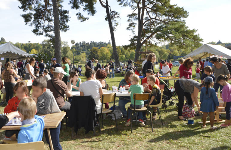 En plein air, sur l'Île d'Or, des familles jouent à des jeux de société.