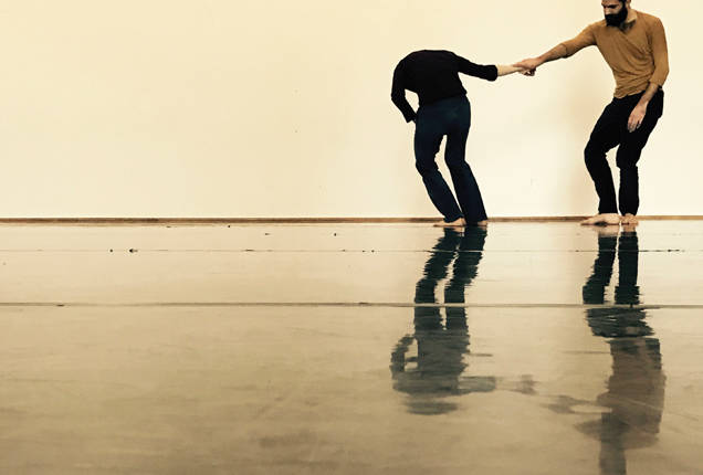 Dans une ambiance de scène dorée, un couple de danseurs se tient sur le côté droit en se tenant par la main.