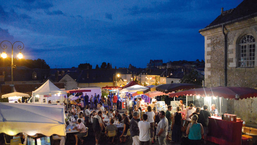 Marché illuminé sur la place Saint-Denis, un soir d'été. Vue imprenable sur le château.