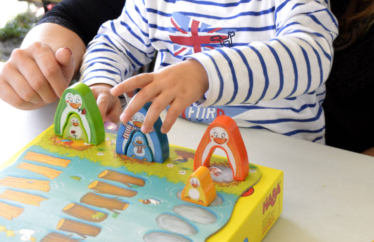 Gros plan sur les mains d'un enfant et d'un adulte en train de jouer à un jeu de société.