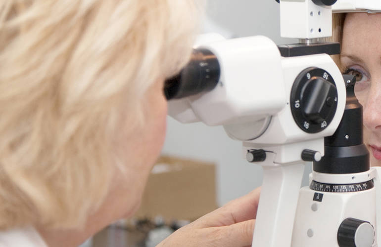 Un ophtalmologue observe les yeux d'un patient avec son appareil.