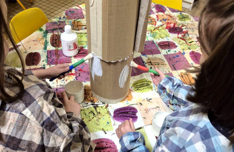 Un groupe d'enfants posent pour la photo autour d'une tortue en papier réalisée par leur soin.
