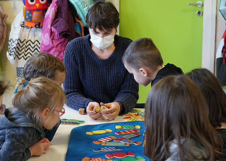 Un groupe d'enfants posent pour la photo autour d'une tortue en papier réalisée par leur soin.