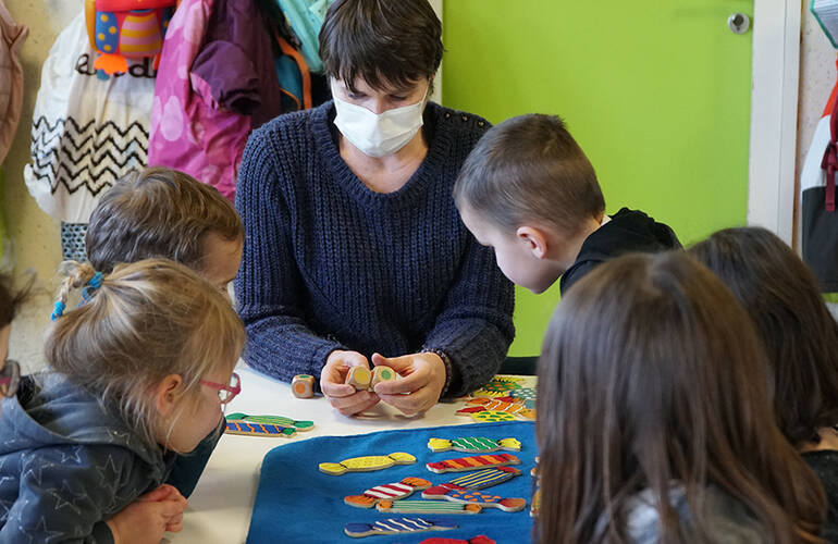 Un groupe d'enfants posent pour la photo autour d'une tortue en papier réalisée par leur soin.