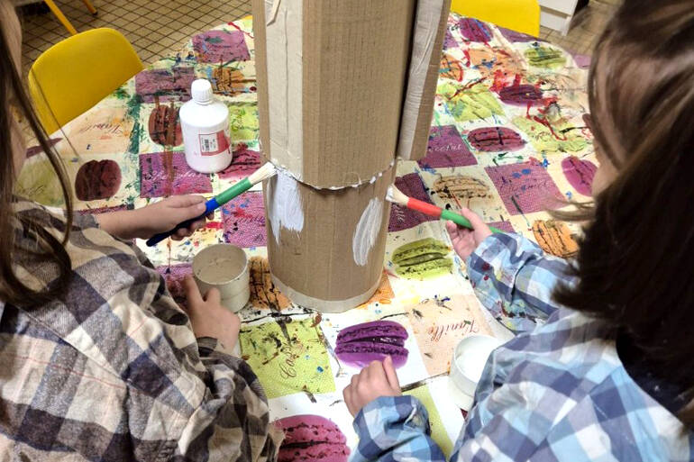 Un groupe d'enfants posent pour la photo autour d'une tortue en papier réalisée par leur soin.