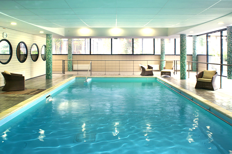 Piscine Domitys Piscine intérieur de la résidence Domitys. Des fauteuils sont installés autour du bassin.