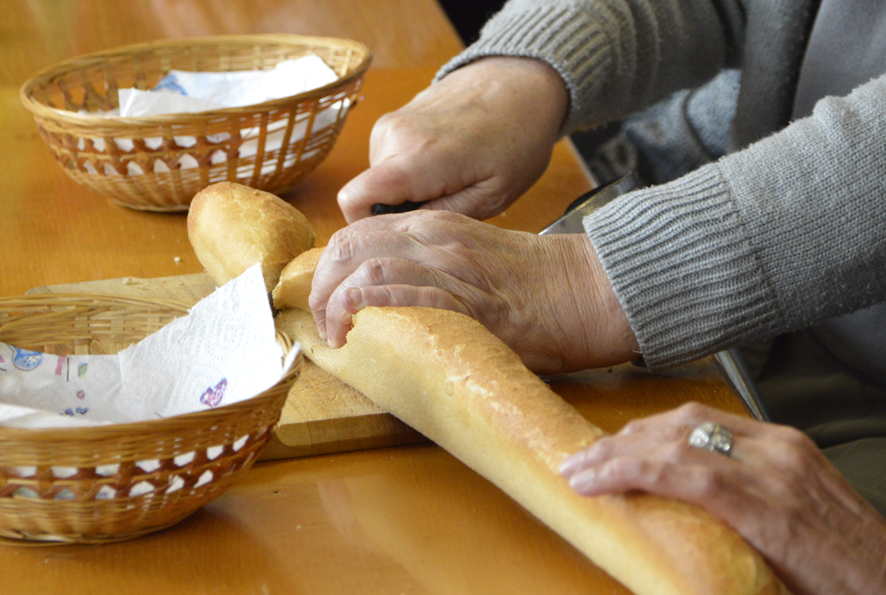 Vue sur des mains en train de découper un morceau de pain.
